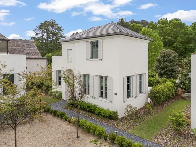 a view of a white house next to a yard with potted plants