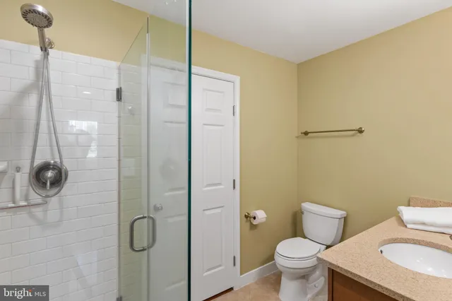 a bathroom with a granite countertop shower a toilet and a sink