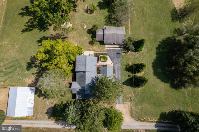 a view of a small house with wooden fence and large trees