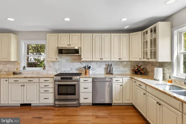 a kitchen with stainless steel appliances granite countertop a stove a sink and white cabinets