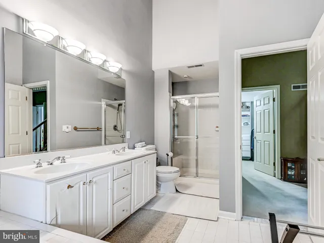 a spacious bathroom with a double vanity sink a large mirror and a shower