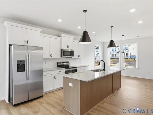 a kitchen with stainless steel appliances granite countertop a sink a stove a refrigerator and island with wooden floor