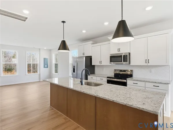 a kitchen with stainless steel appliances granite countertop a sink a stove a microwave a counter top space and cabinets