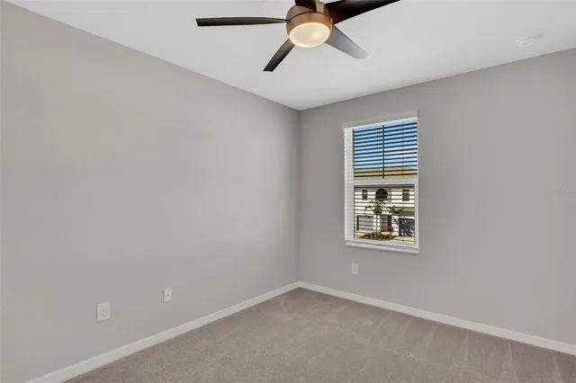 an empty room with a window and a ceiling fan