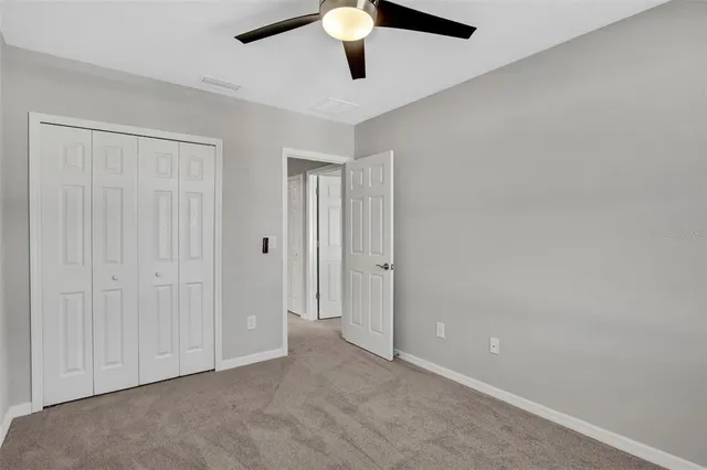 an empty room with closet and a chandelier fan