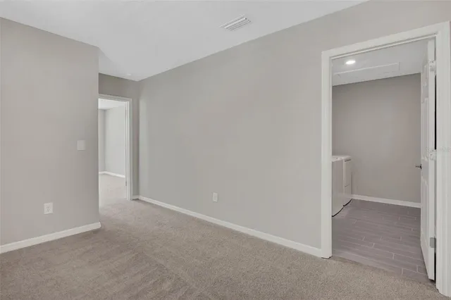 an empty room with chandelier fan and windows