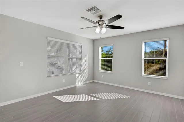 a view of an empty room with a window and wooden floor