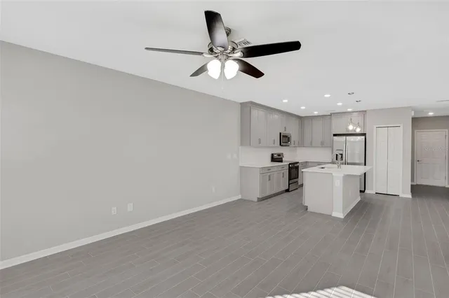 a view of an empty room and kitchen with a sink
