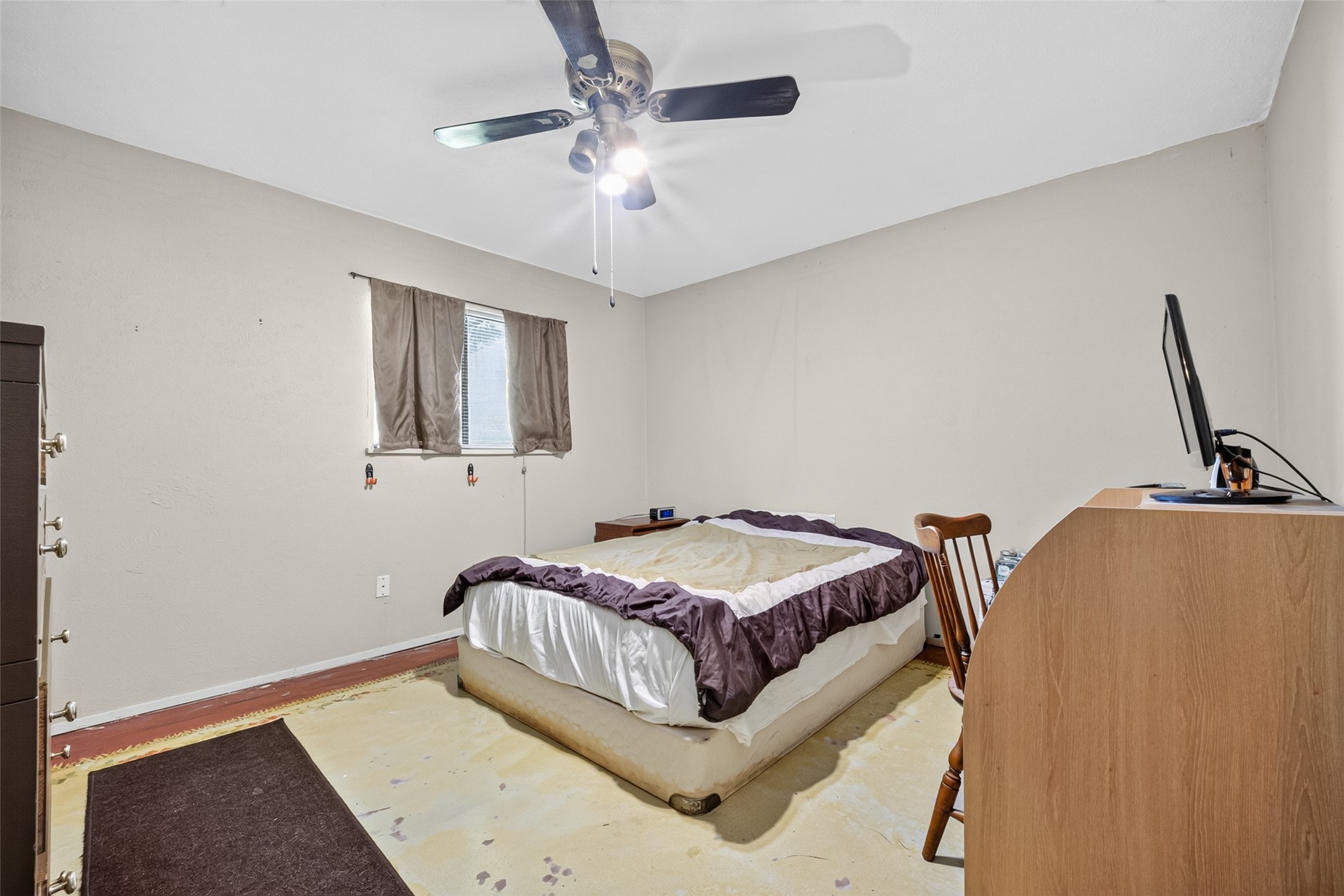 22926 Millgate Drive Spring, TX 77373 - Photo 17 of 34 This bedroom features neutral walls, a ceiling fan, and natural light from a window. It contains a bed, a dresser, and a small desk setup, offering a simple and functional space.