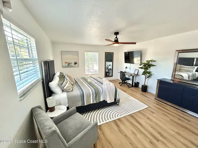 a bedroom with a bed a chair and a flat screen tv