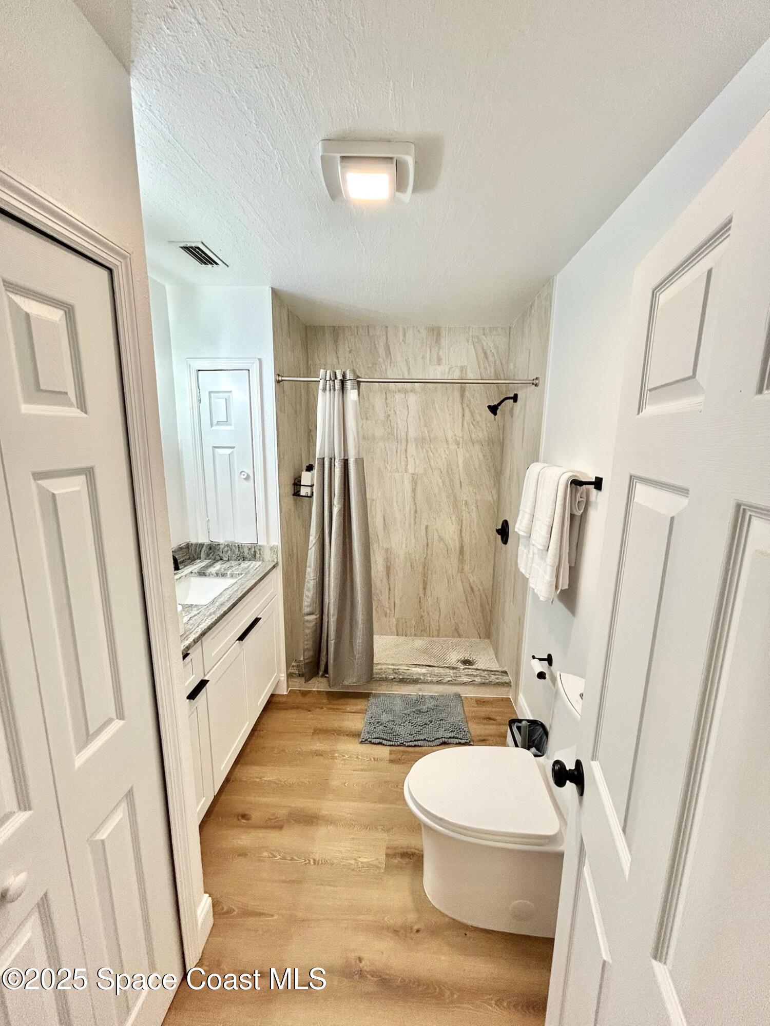 8110 Canaveral Boulevard, Unit 3 Cape Canaveral, FL 32920 - Photo 21 of 25 a bathroom with a sink a toilet a mirror a vanity and a shower