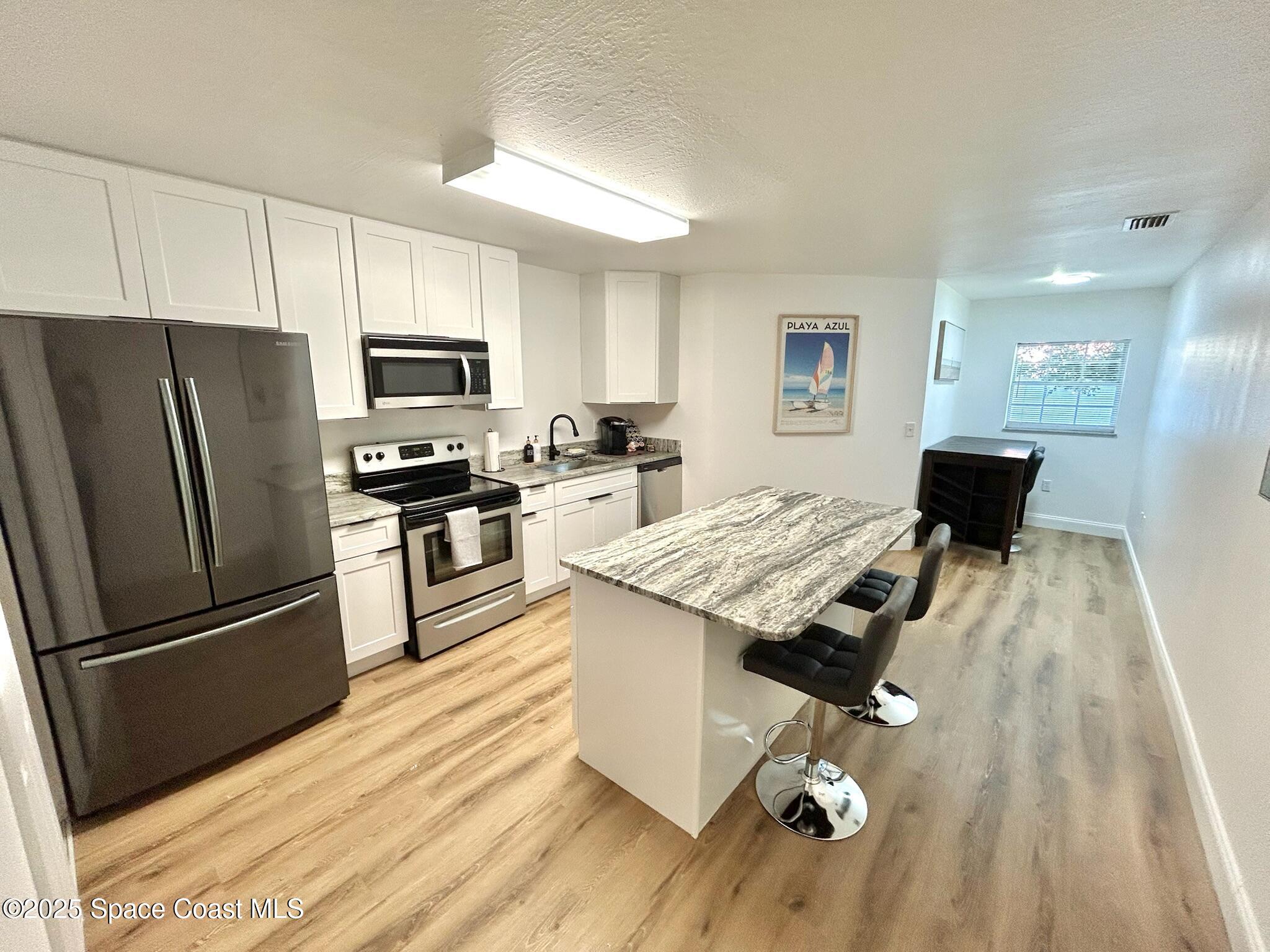 8110 Canaveral Boulevard, Unit 3 Cape Canaveral, FL 32920 - Photo 5 of 25 a kitchen with a stove a refrigerator and a stove top oven