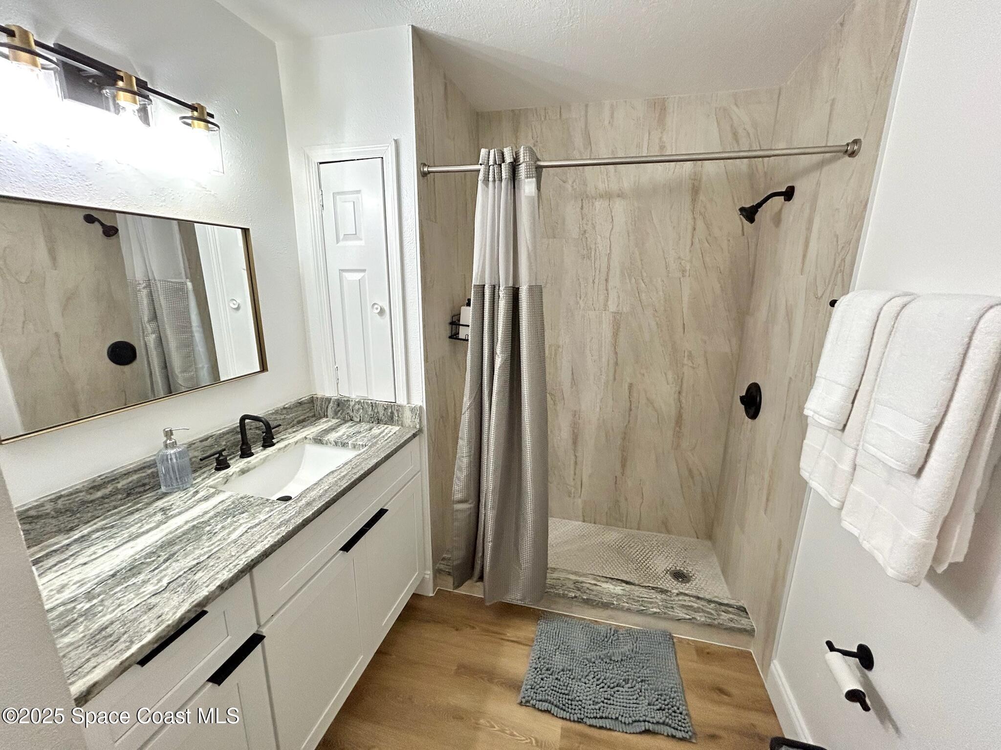 8110 Canaveral Boulevard, Unit 3 Cape Canaveral, FL 32920 - Photo 6 of 25 a bathroom with a granite countertop shower sink vanity and mirror