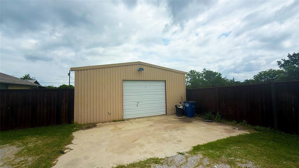 1356 Kerry Lane Azle, TX 76020 - Photo 5 of 27 Freestanding metal garage with a white roll-up door and exterior lighting fixture