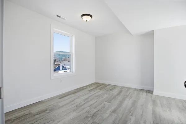an empty room with wooden floor and windows