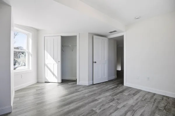 an empty room with wooden floor and windows