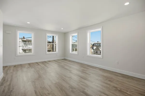a view of an empty room with window and wooden floor