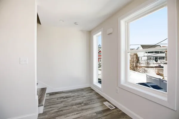 a view of an empty room with wooden floor and a window