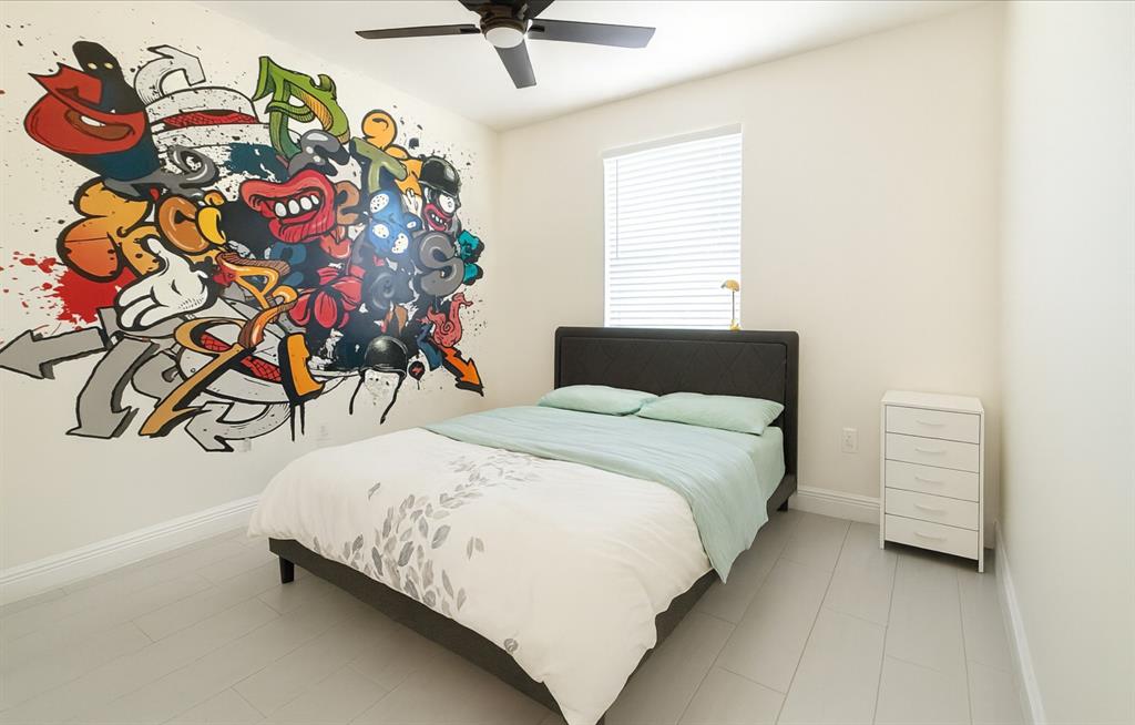 18702 Southwest 27th Street Miramar, FL 33029 - Photo 14 of 17 a bedroom with a bed and a painting on the wall