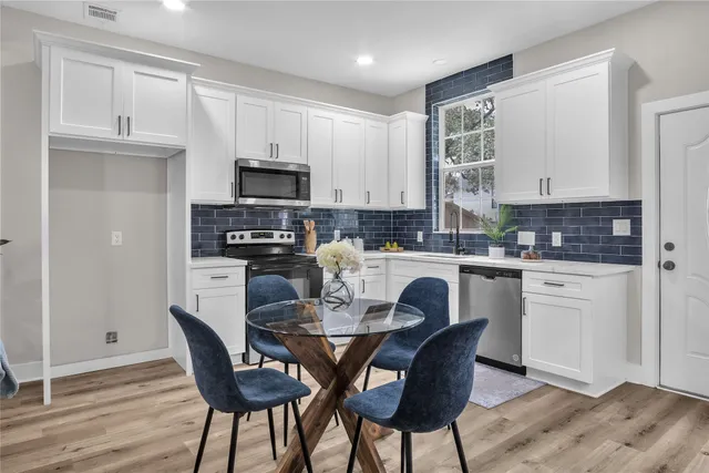 a kitchen with stainless steel appliances granite countertop a table chairs microwave and sink