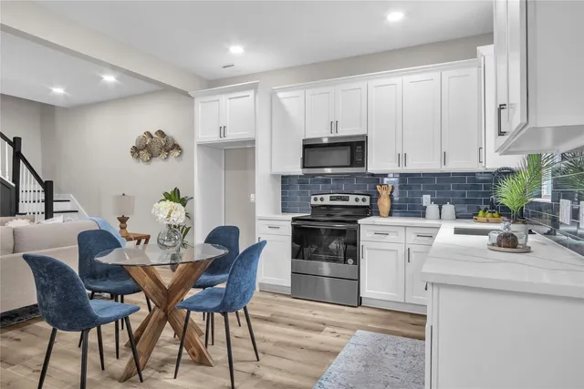 a kitchen with stainless steel appliances a stove a sink a microwave a refrigerator and white cabinets