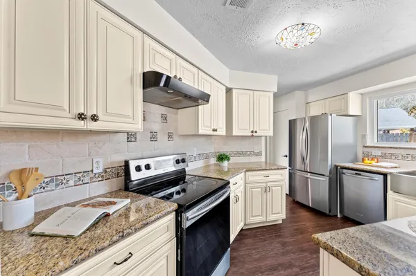a kitchen with stainless steel appliances granite countertop a sink stove and refrigerator