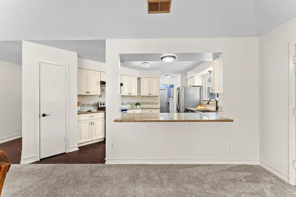 a kitchen with stainless steel appliances granite countertop a refrigerator a sink and white cabinets