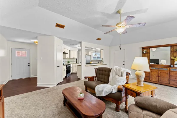 a living room with furniture kitchen view and a chandelier
