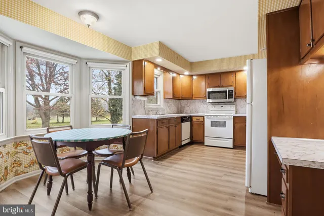 a kitchen with stainless steel appliances granite countertop wooden cabinets a dining table and chairs