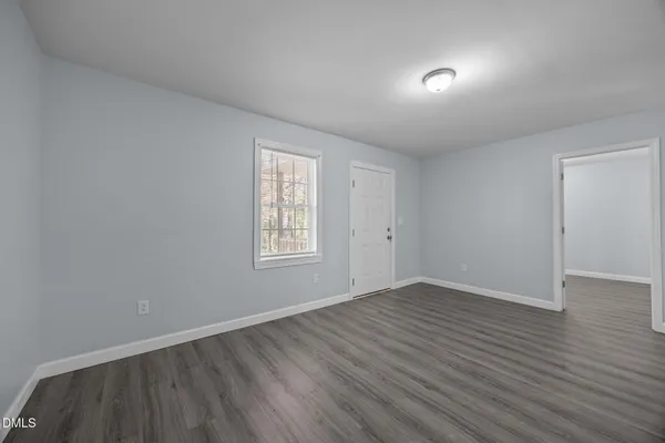 a view of an empty room with wooden floor and closet