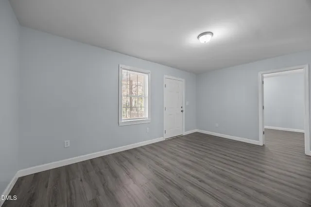 a view of an empty room with wooden floor and closet