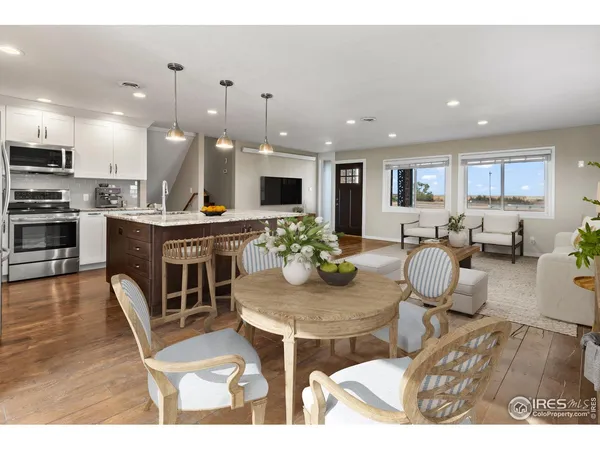 a living room with furniture kitchen view and a wooden floor