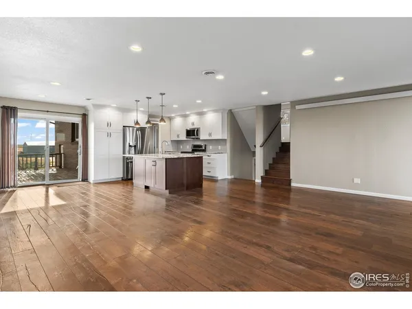 a view of a living room a refrigerator and a wooden floor