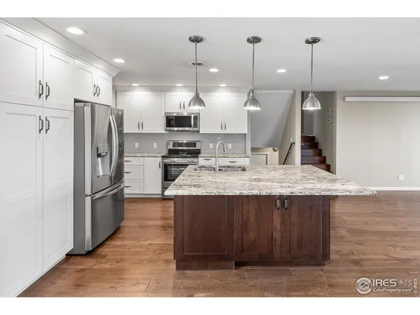 a kitchen with stainless steel appliances kitchen island granite countertop a refrigerator a stove a sink and a oven