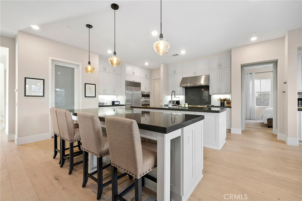70 Ray Irvine, CA 92618 - Photo 7 of 41 a large kitchen with kitchen island a dining table chairs and a wooden floor