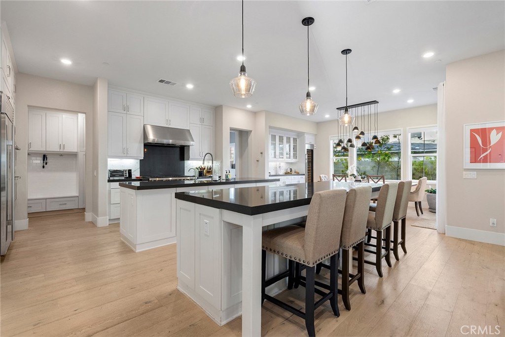 70 Ray Irvine, CA 92618 - Photo 8 of 41 a kitchen with stainless steel appliances kitchen island granite countertop a stove a refrigerator a kitchen island a dining table and chairs with wooden floor