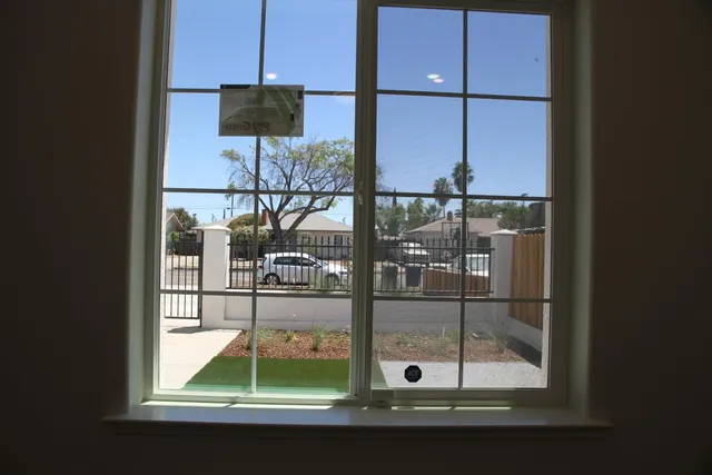 a view of an empty room with wooden floor and a fan