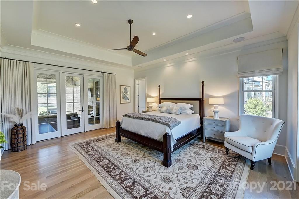 3452 Foxcroft Road Charlotte, NC 28211 - Photo 23 of 48 a spacious bedroom with a bed a couch and a dresser with wooden floor