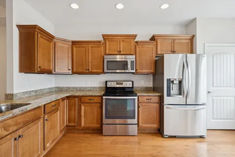a kitchen with stainless steel appliances granite countertop a refrigerator stove top oven and sink