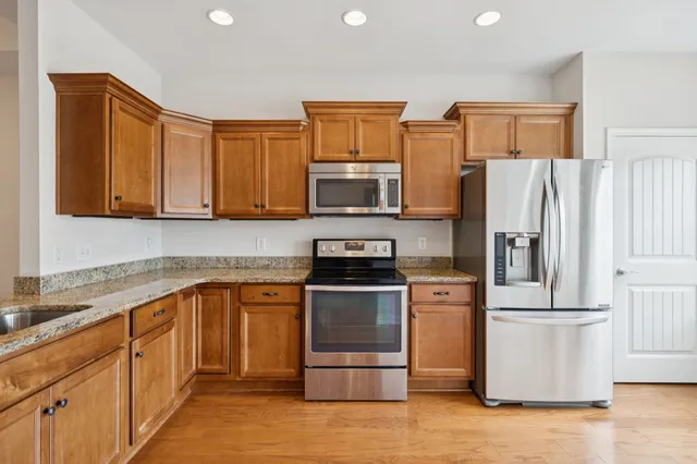 a kitchen with stainless steel appliances granite countertop a refrigerator stove top oven and sink