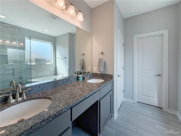 a bathroom with a granite countertop double vanity sink and a mirror