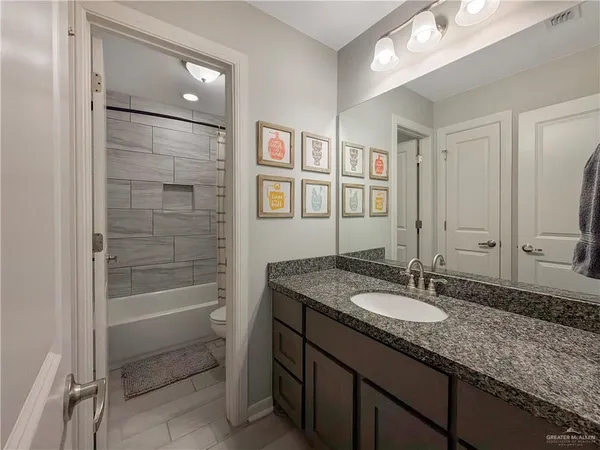 a bathroom with a granite countertop sink a mirror and a bathtub