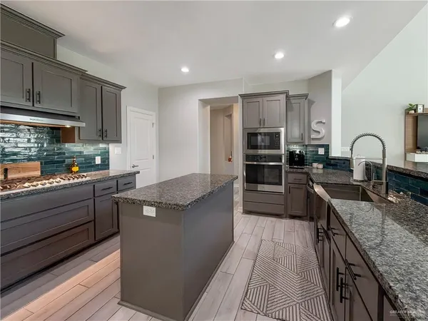 a kitchen with stainless steel appliances granite countertop a stove top oven a sink and dishwasher
