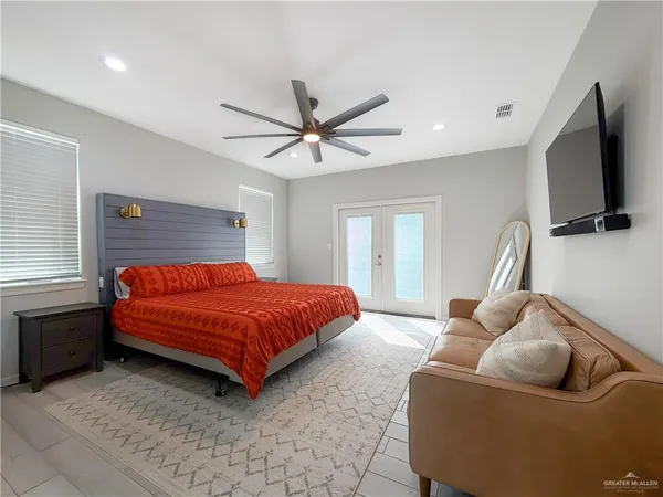 a spacious bedroom with a bed and a flat screen tv