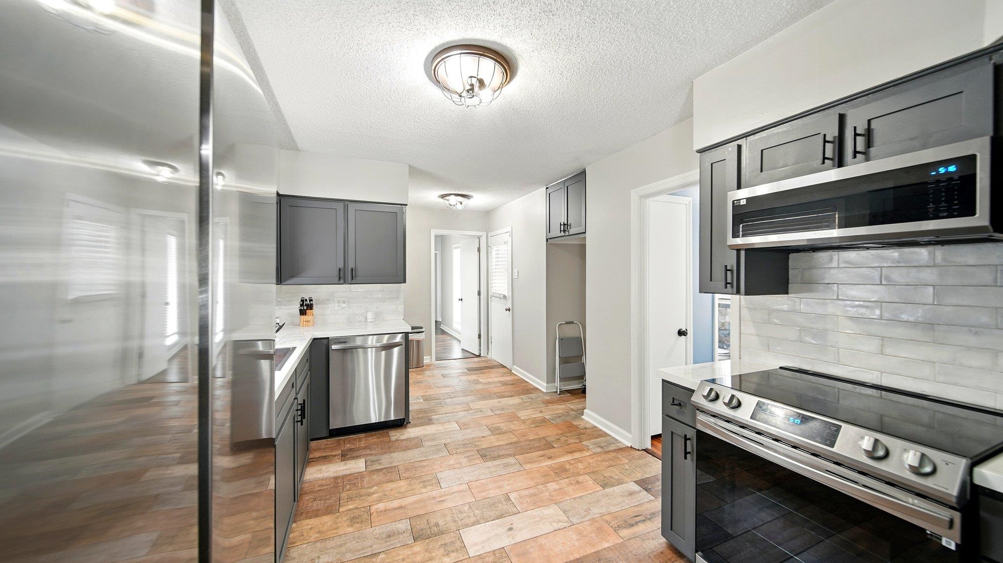 359 South Fenwick Road Memphis, TN 38111 - Photo 13 of 31 Kitchen featuring stainless steel appliances, gray cabinets, backsplash, a textured ceiling, and light wood-style floors