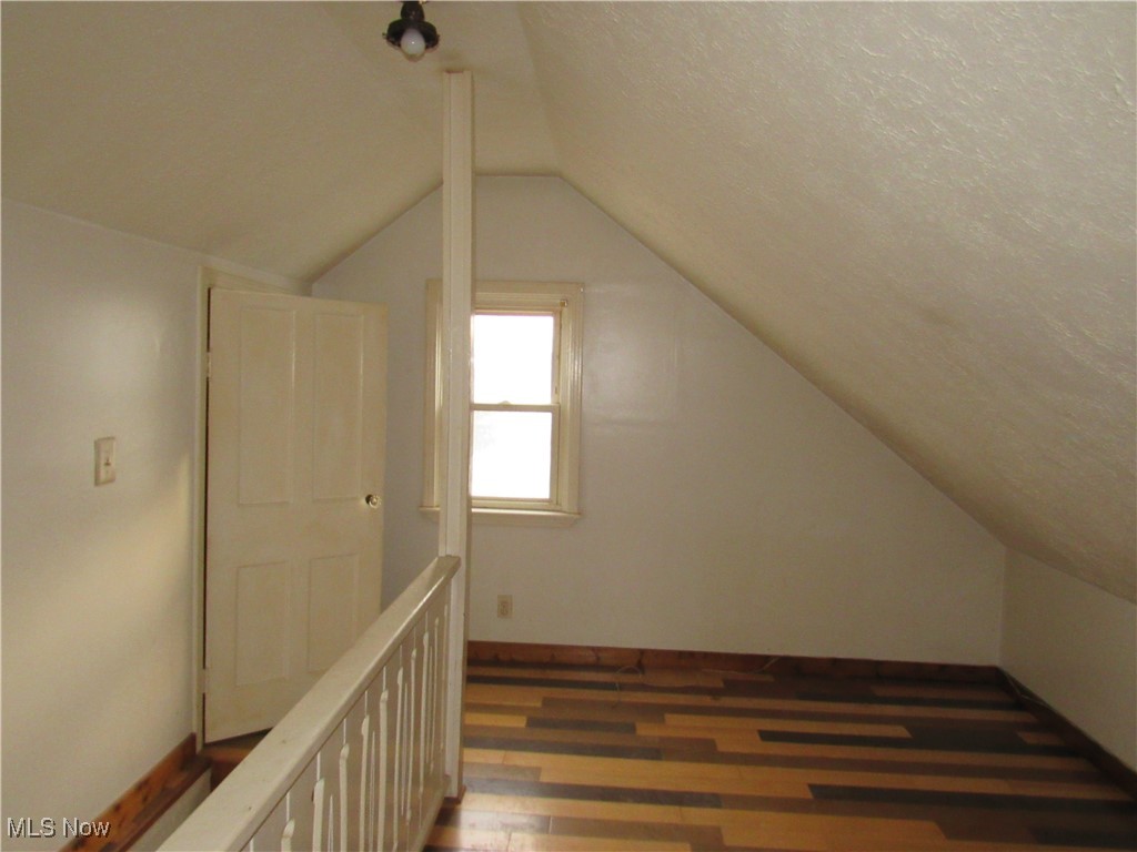 4550 Effie Road Cleveland, OH 44105 - Photo 20 of 29 Additional living space with dark wood-style flooring, vaulted ceiling, and a textured ceiling