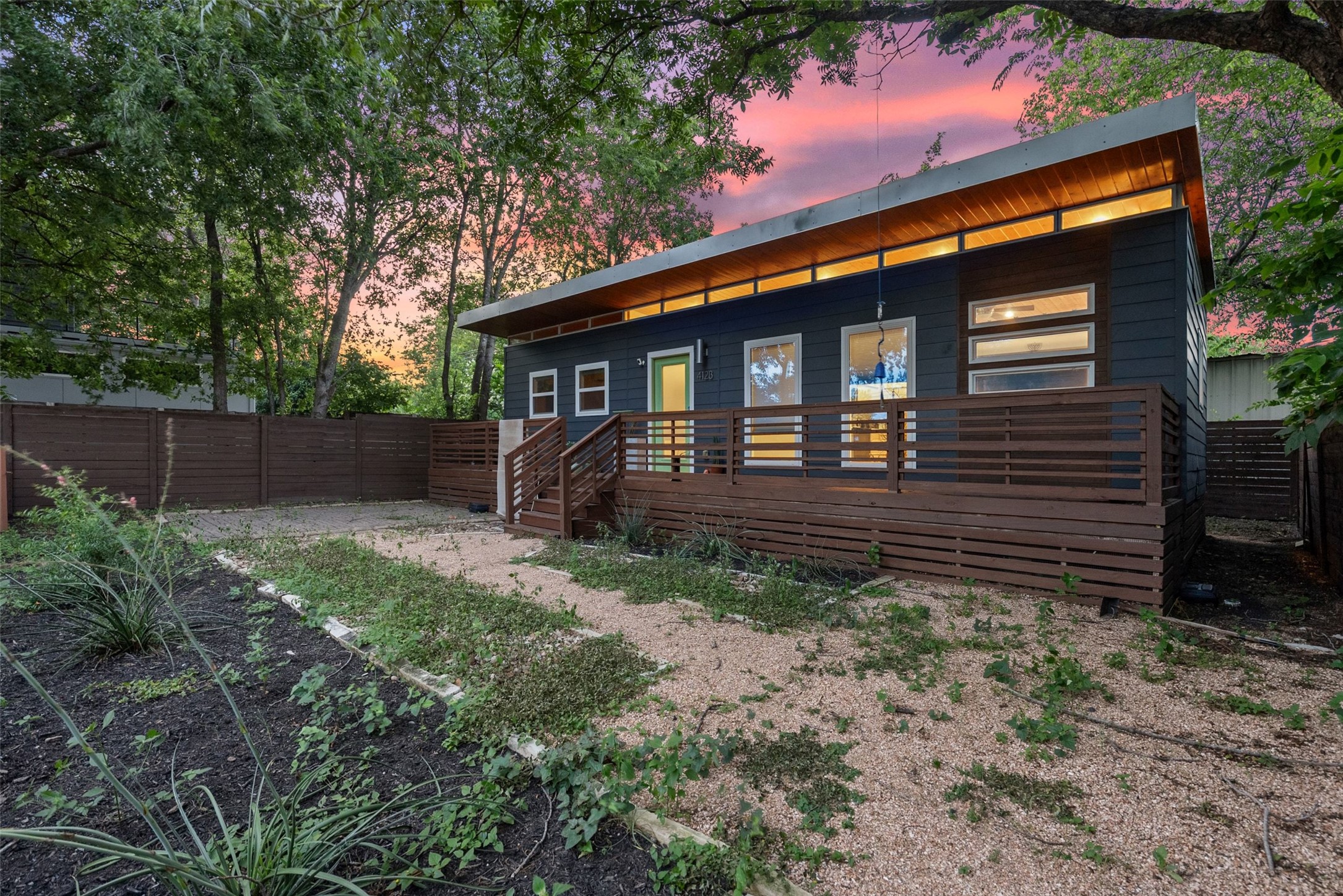 412 West Croslin Street Austin, TX 78752 - Photo 22 of 36 A modern facade with a broad deck offers outdoor living space beneath a dramatic sunset.