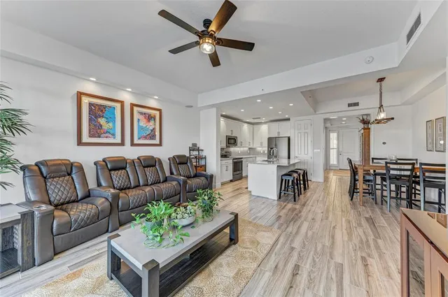 a kitchen with stainless steel appliances kitchen island granite countertop a stove top oven a sink a dining table and chairs with wooden floor