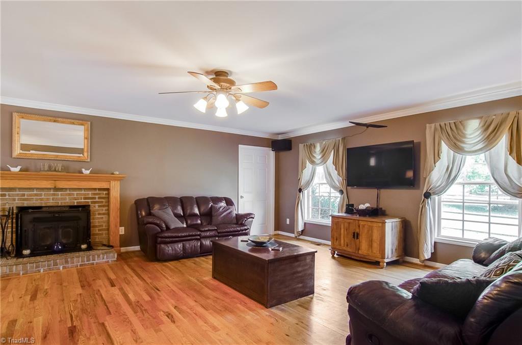 7607 Strawberry Road Summerfield, NC 27358 - Photo 11 of 30 Spacious living room with gleaming hardwoods. The fireplace has a wood stove insert and blower to warm during those winter months.