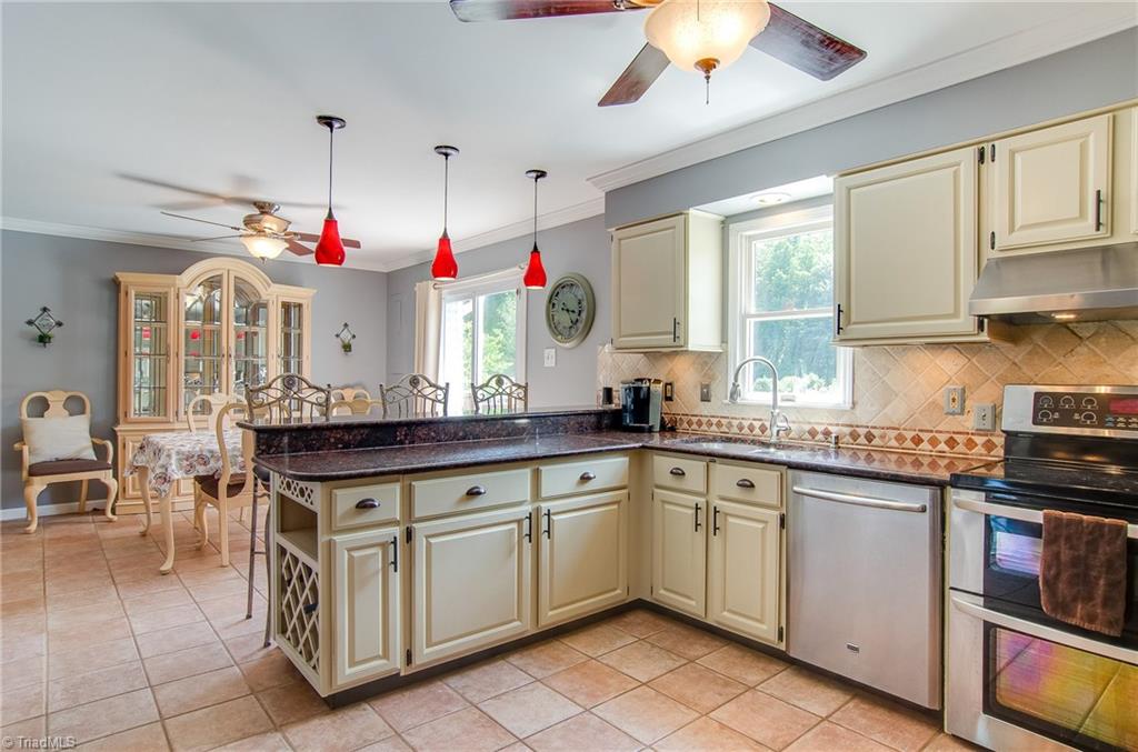7607 Strawberry Road Summerfield, NC 27358 - Photo 15 of 30 Bar seating and dining area allow family and friends to interact with the kitchen cook. The windows overlook the pool area.